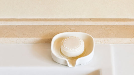 Ceramic self draining soap dish with natural bar soap on a bathroom sink, handmade ceramic soap holder for a modern eco-friendly bathroom.