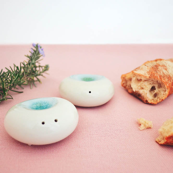 style photo of modern minimalist salt and pepper shakers in smooth high-fired porcelain, sculptural stone form. Home decor by Maia Ming Designs, food-safe artisan pottery from Barcelona for mindful daily rituals and refined interior styling.